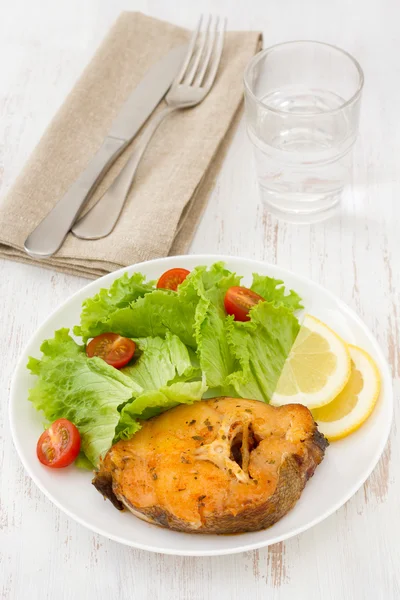 Fish with salad and lemon on the white plate — Stock Photo, Image