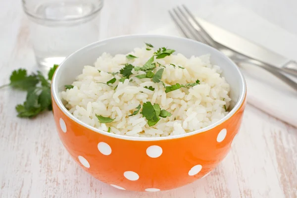 Boiled rice in orange bowl with parsley — Stock Photo, Image