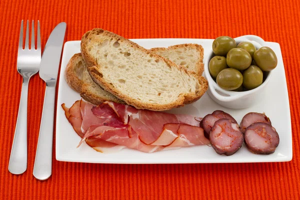Prosciutto, sausages and olives on the plate — Stock Photo, Image