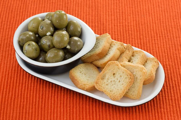 Olives in bowl and small toasts — Stock Photo, Image