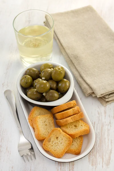 Olives in bowl and small toasts — Stock Photo, Image