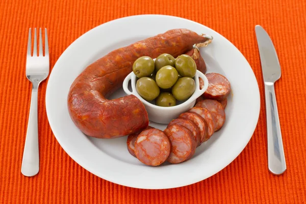 Сосиски с оливками на белой тарелке — стоковое фото