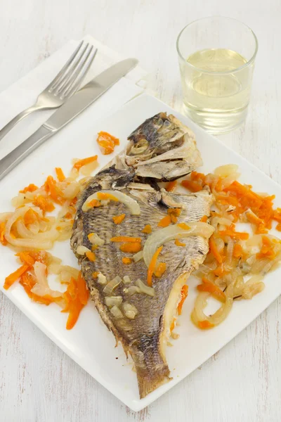 Рыба с луком и морковью на белой тарелке — стоковое фото