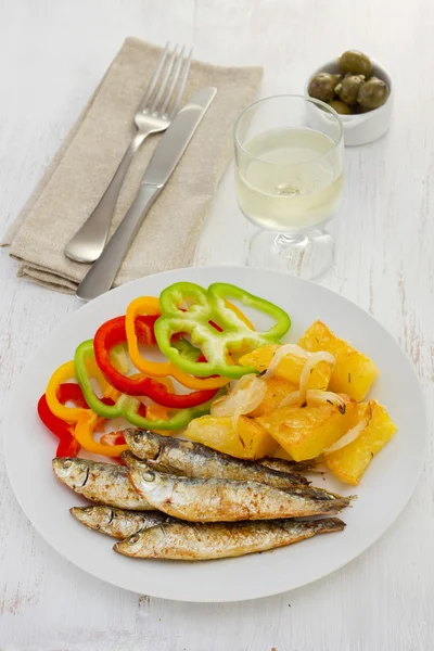 Smažené sardinky s brambor a sklenicí vína — Stock fotografie