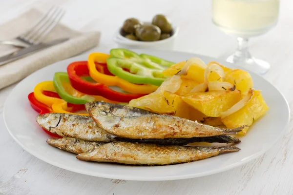 Smažené sardinky s brambor a sklenicí vína — Stock fotografie
