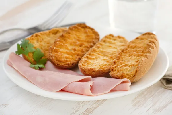 Pani tostati con prosciutto sul piatto bianco — Foto Stock
