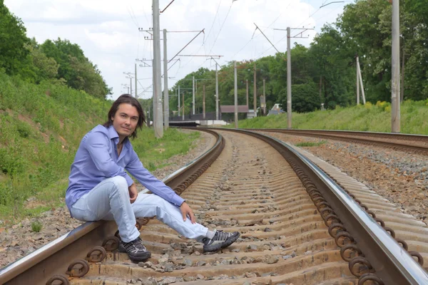 Man sitting on the railroad tracks — Stock Photo, Image