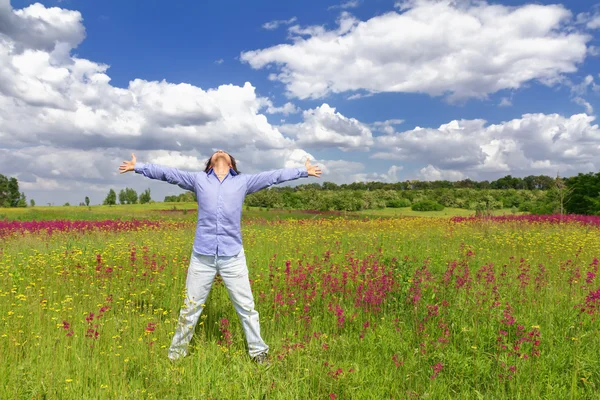Young man standing on a meadow on a blue sky background — Stock Photo, Image