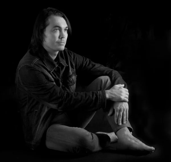Młody człowiek siedzi na podłodze (czarno-biały) — Zdjęcie stockowe