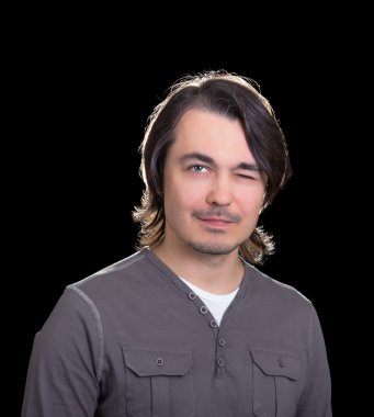 Young man winking, on black background