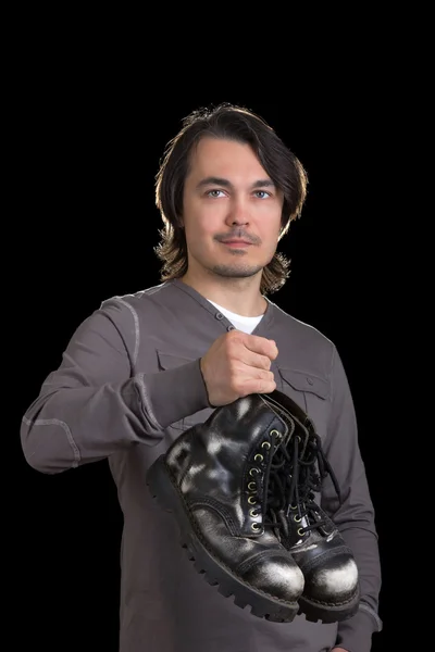 Young man holding old black boots in his hands — Stock Photo, Image
