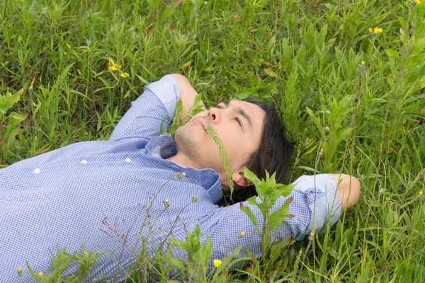 Genç adam çimlerin üzerinde yatıyor. — Stok fotoğraf