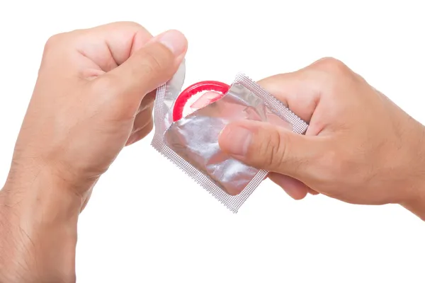Homem está abrindo um preservativo, isolado em branco — Fotografia de Stock