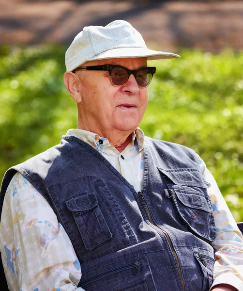 Старший щасливий чоловік сидить у парку — стокове фото