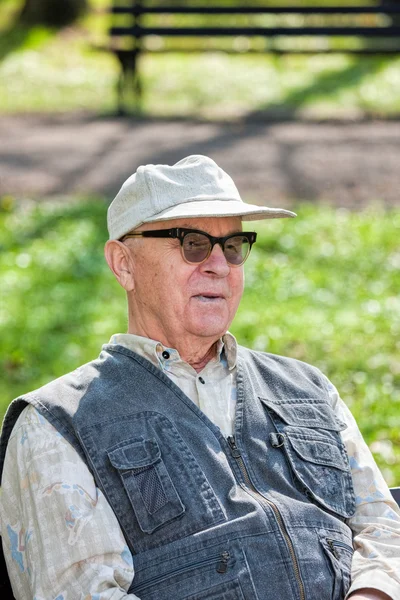 Senior feliz homem sentado no parque — Fotografia de Stock