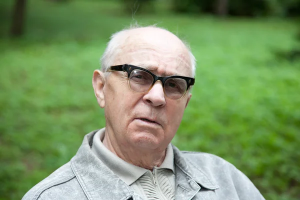 Senior gelukkig man zit in het park — Stockfoto