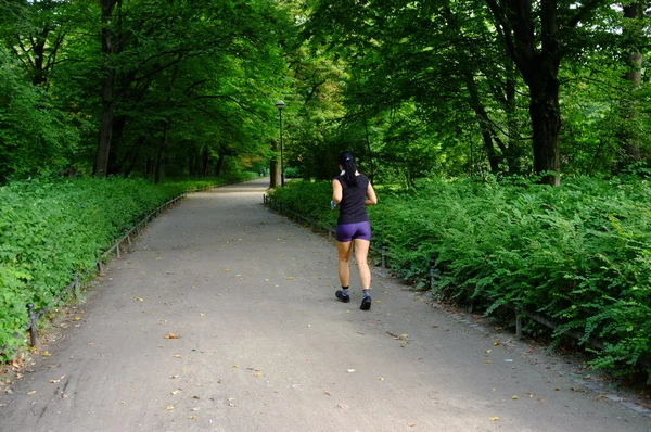 Ung vacker kaukasisk kvinna jogging i sommaren park. — Stockfoto