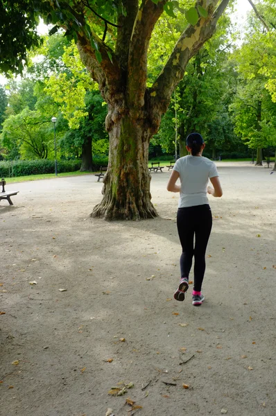 Ung vacker kaukasisk kvinna jogging i sommaren park. — Stockfoto