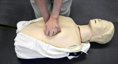 Man practicing CPR techniques on dummy. clipart