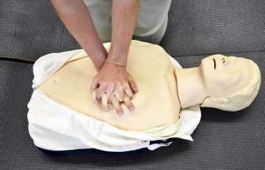 Man practicing CPR techniques on dummy. clipart