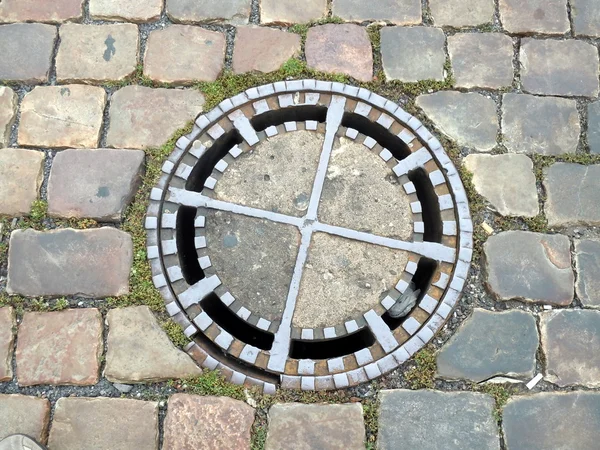 Rock ground with an iron manhole cover — Stock Photo, Image