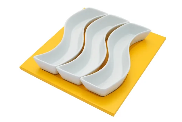 Tre piatti bianchi su un tagliere giallo — Foto Stock
