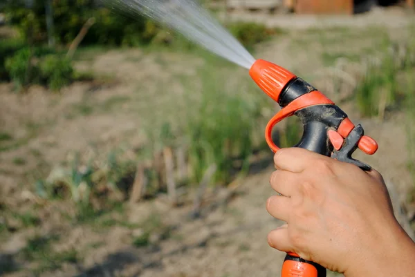 Hand with a water gun in the garden — Stock Photo, Image