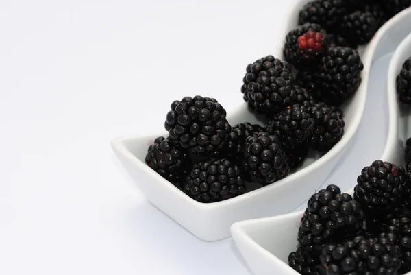 stock image Juicy blackberries into shaped dishes, on white background soft shadows