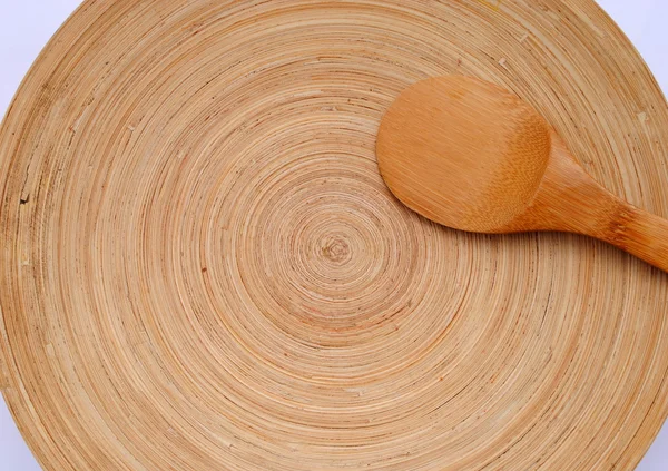 Colher de madeira em uma placa de bambu redonda — Fotografia de Stock