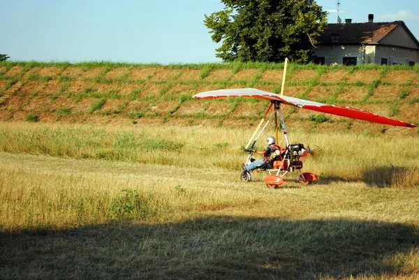 Colorful hang glider takes off in farmland landscape — Stock Photo, Image