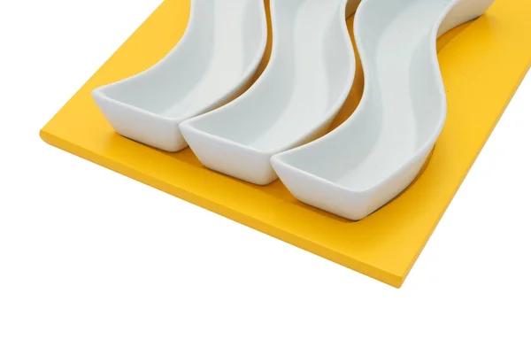 Tres platos blancos sobre una tabla de cortar amarilla — Foto de Stock