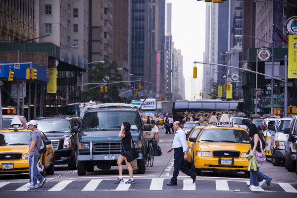Crossing street in New York, with cabs and many cars on the background.