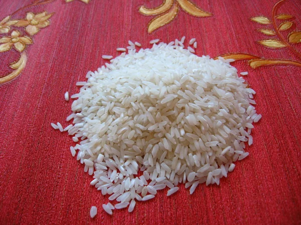 Verstreuter Reis auf rotem Hintergrund — Stockfoto