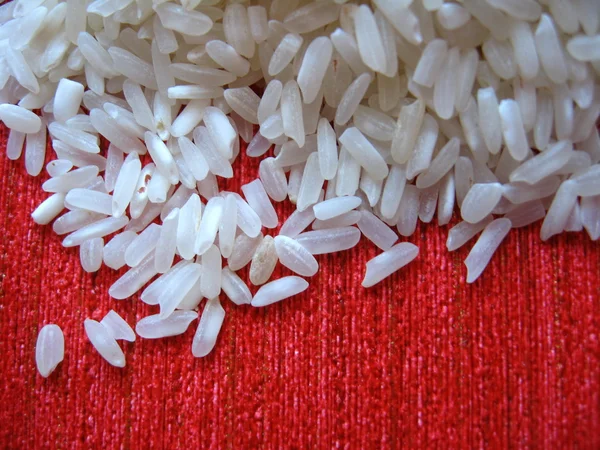Egy piros háttérben a szétszórt rizs — Stock Fotó
