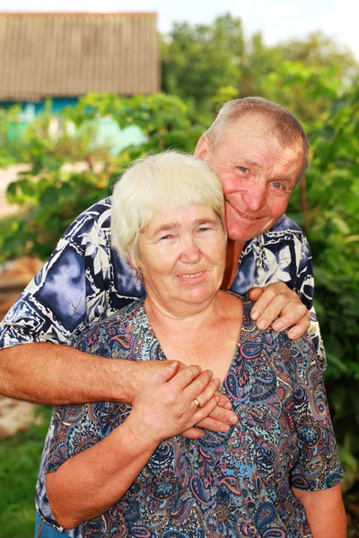 Lächelndes Seniorenpaar, das sich im Freien umarmt Stockbild