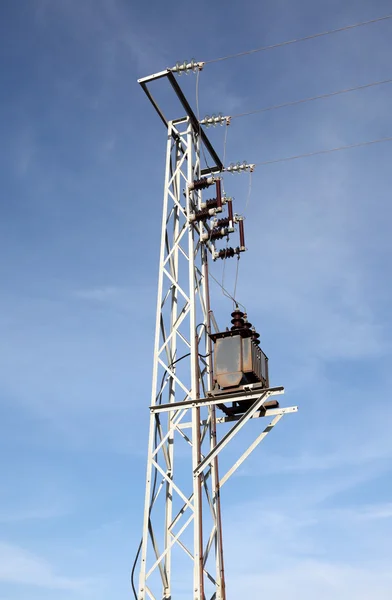 Силовой столб с трансформатором против голубого неба — стоковое фото
