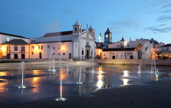 Praça da cidade de Lagos com fontes iluminadas ao entardecer. Algarve Portugal . — Fotografia de Stock