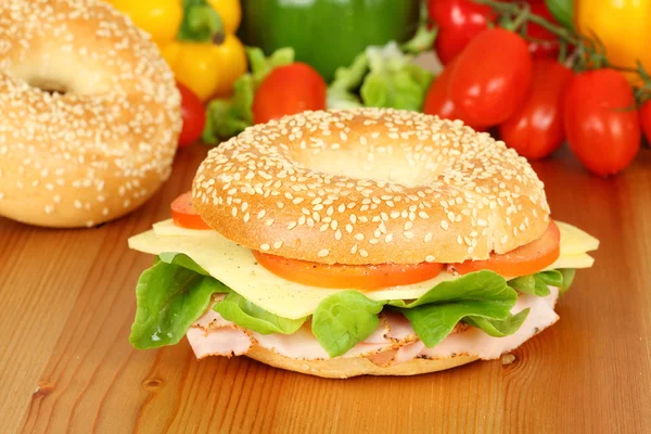 Fresh bagel with turkey breast, cheese, salad and tomatoes — Stock Photo, Image