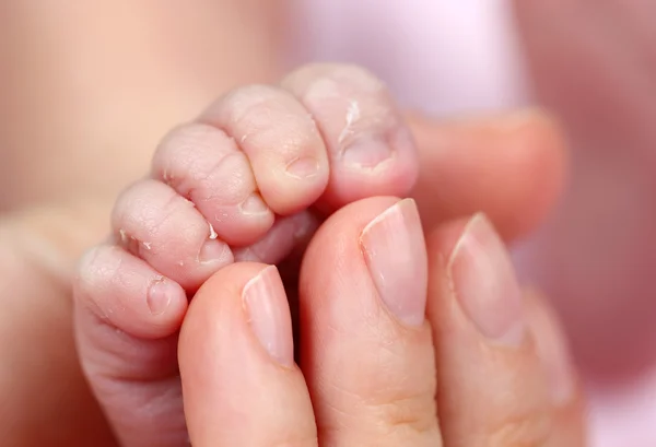 Foot of newborn baby and mothers fingers — Stock Photo, Image