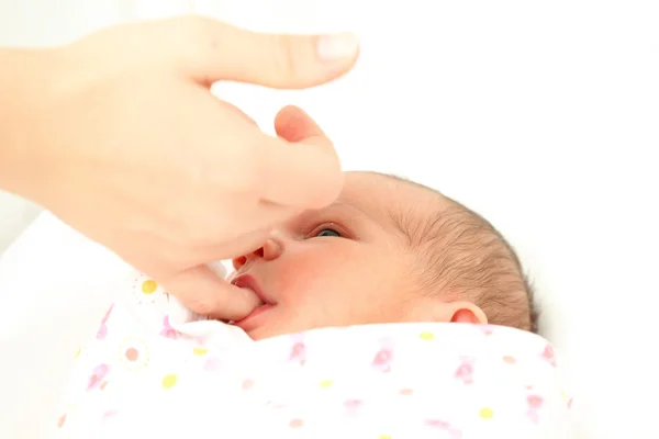 Newborn baby sucking on mothers finger — Stock Photo, Image
