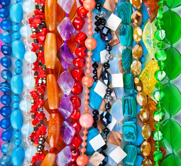 Viele farbige Perlen aus verschiedenen Mineralien und Steinhintergründen — Stockfoto