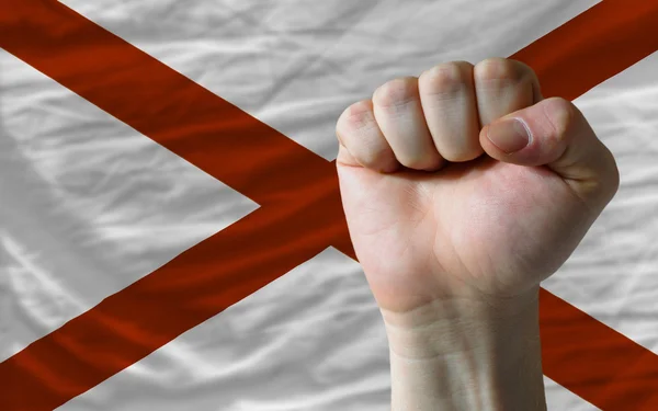 Us state flag of alabama with hard fist in front of it symbolizi — Stock Photo, Image