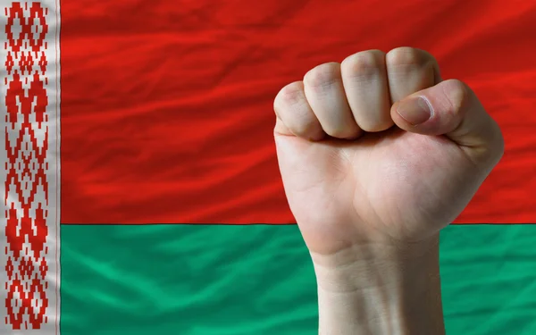 Pugno duro davanti alla bandiera bielorussa che simboleggia il potere — Foto Stock