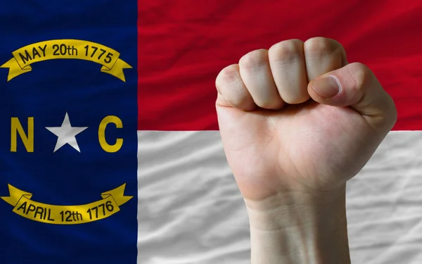 Us state flag of north carolina with hard fist in front of it sy — Stock Photo, Image
