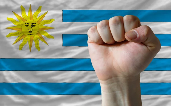 Hard fist in front of uruguay flag symbolizing power — Stock Photo, Image