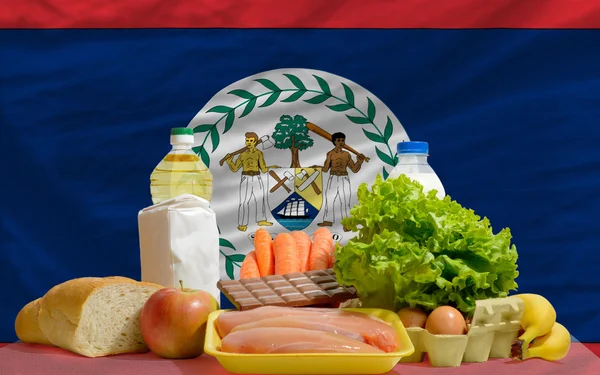 Abarrotes de alimentos básicos frente a la bandera nacional de Belice — Foto de Stock