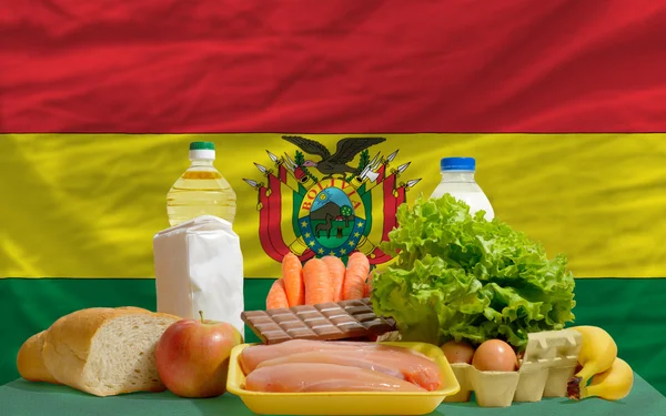Abarrotes de alimentos básicos frente a la bandera nacional de Bolivia — Foto de Stock