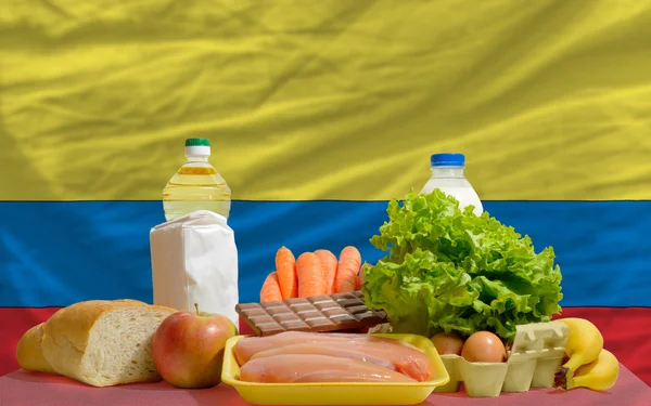 Abarrotes básicos de alimentos frente a la bandera nacional de Colombia — Foto de Stock