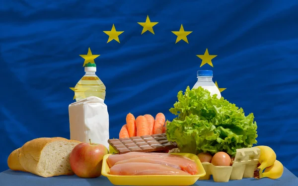 Abarrotes de alimentos básicos frente a la bandera nacional de Europa — Foto de Stock