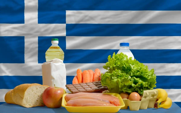 Abarrotes de alimentos básicos frente a la bandera nacional griega — Foto de Stock